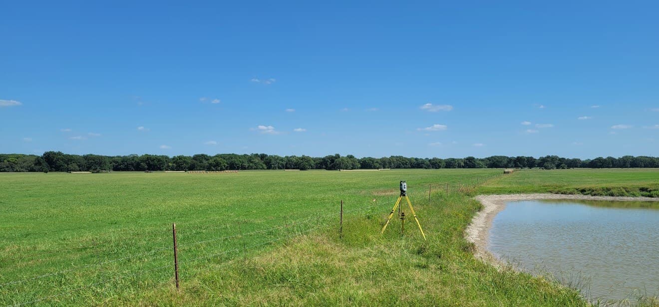 Acreage property with a pond and open field during a Roome Land Surveying boundary survey.