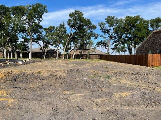 Graded and compacted building pad on a treed lot ahead of forming.