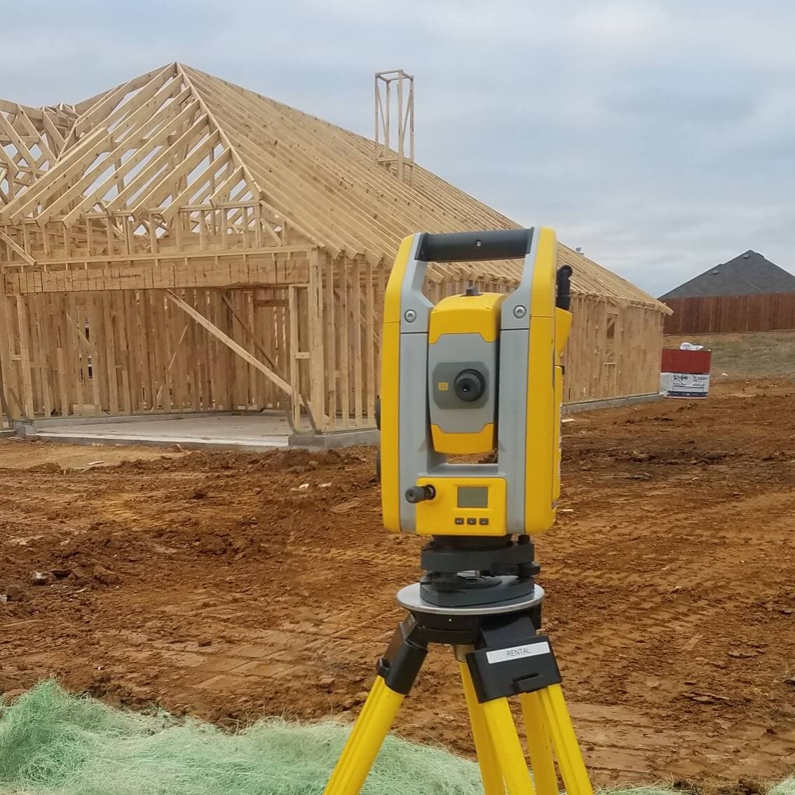 Surveying instrument set up in front of a home under construction during a Roome Land Surveying site visit