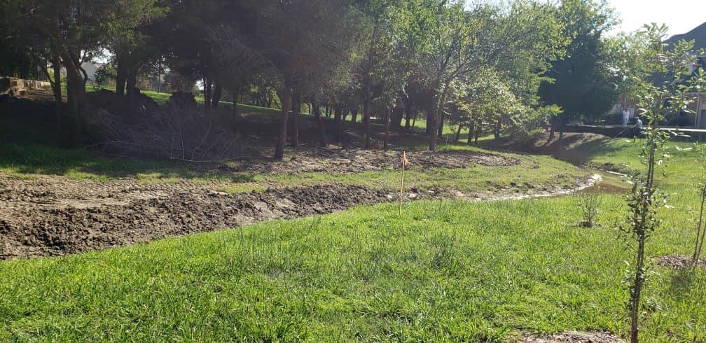 Drainage channel and graded bank on a residential property during a topographic survey.